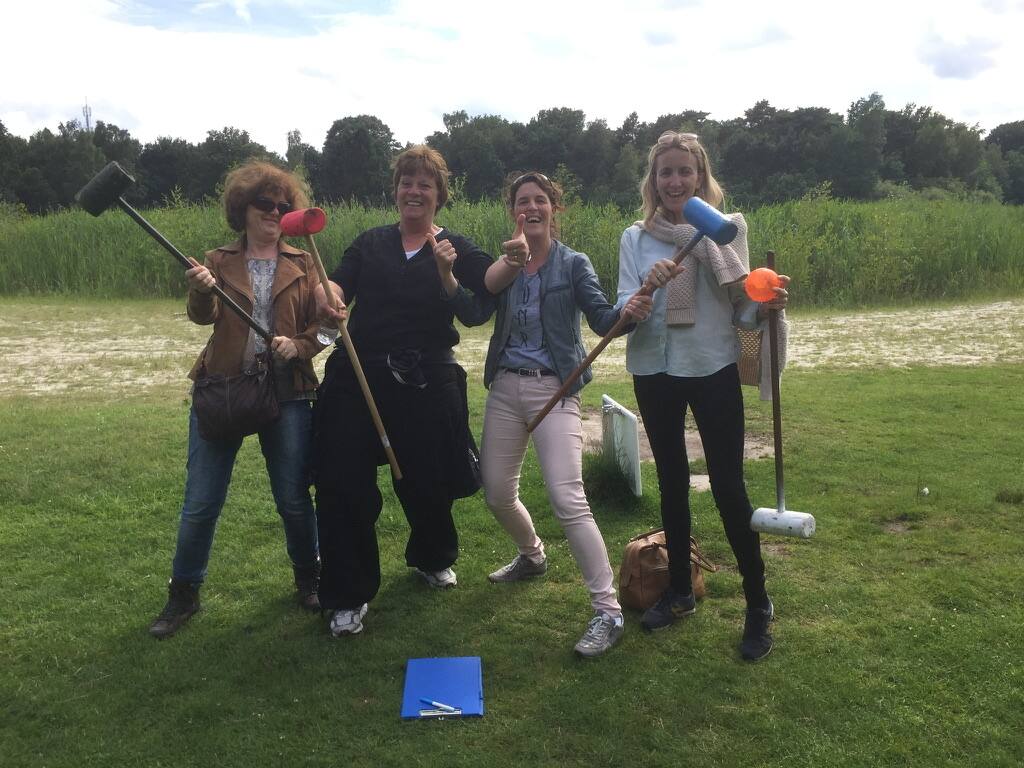 Vier enthousiaste deelneemsters poseren met hun bosgolf-sticks na afloop