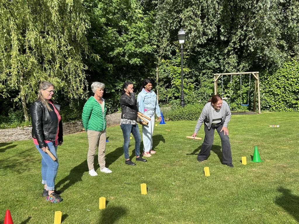 Deelnemer plaatst een houten blok terwijl het team toekijkt tijdens Kubb in het park